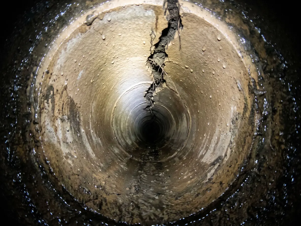 Sewer camera view of a longitudinal crack along a clay sewer pipe